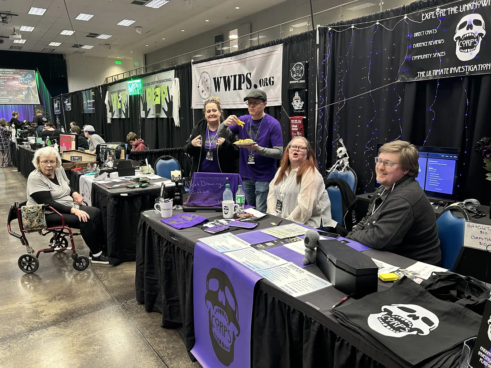 A paranormal investigation team at their purple-draped booth